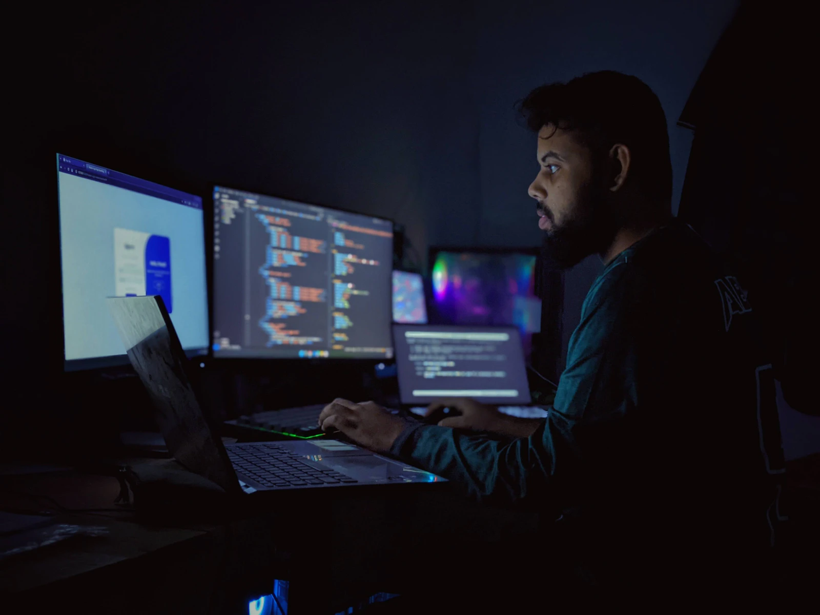 Man working at a desk with several screens in the evening