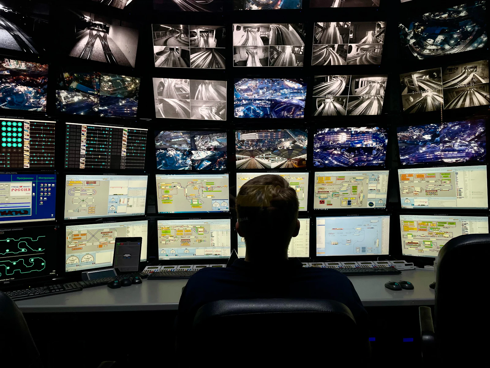 Person at a control desk watching a wall of monitors
